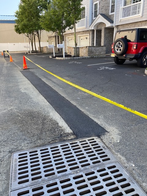 Long asphalt drainage repair beside a residential parking area