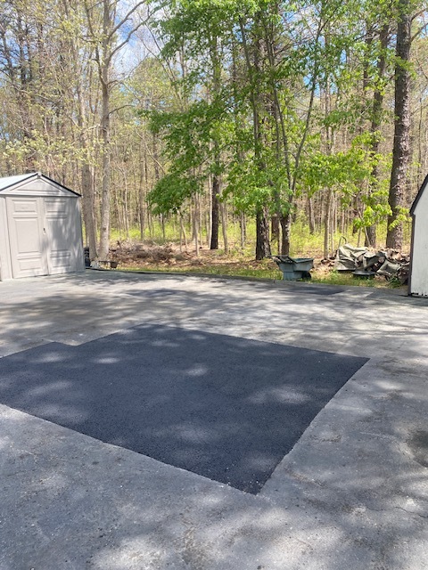 Completed square asphalt repair on a residential driveway